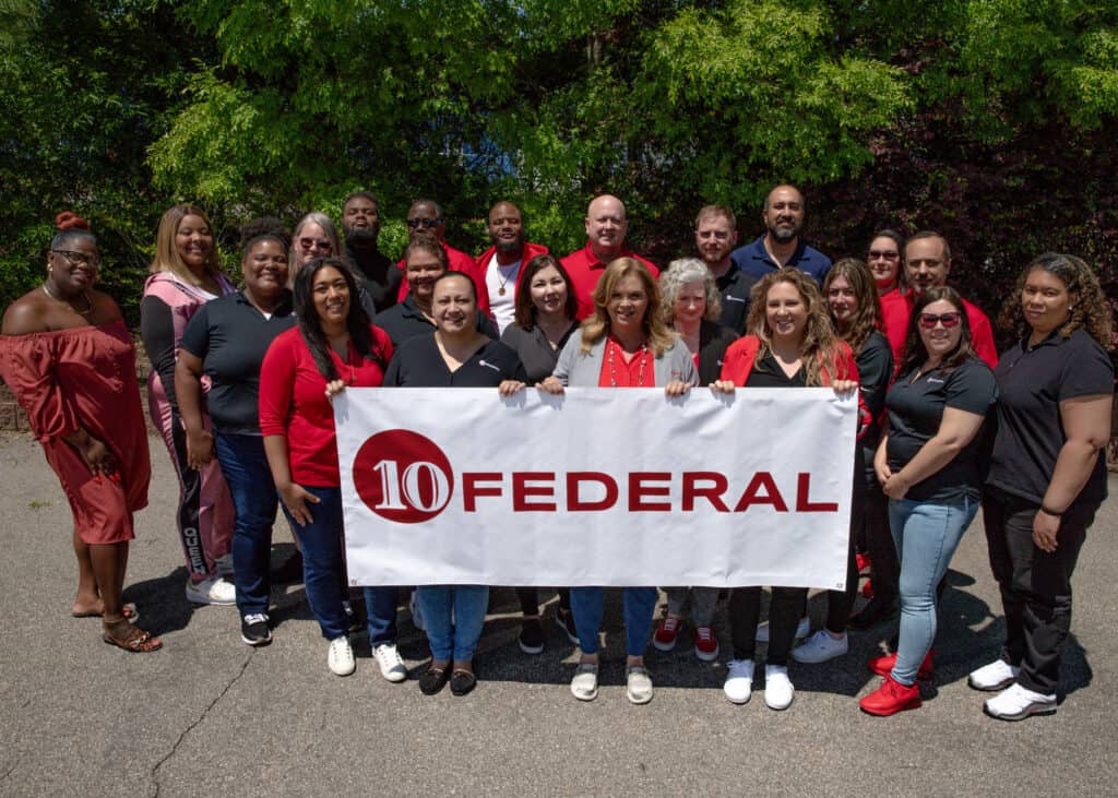 10 Federal Company Photo of employees outside holding a 10 Federal Banner